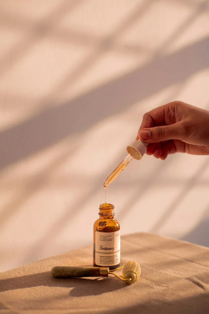 Mão segurando um conta-gotas de sérum, em luz quente de janela